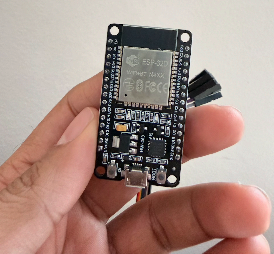 ESP32-WROOM-32 devkit held in hand, jumper wires attached